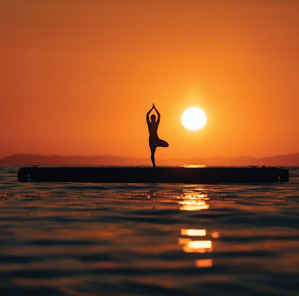 A woman practices yoga at sunset during one of the complementary Secasana yoga classes offered at Islas Secas | Islas Secas